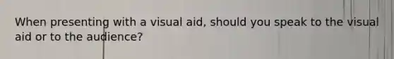 When presenting with a visual aid, should you speak to the visual aid or to the audience?