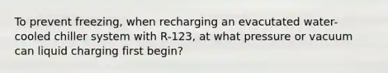 To prevent freezing, when recharging an evacutated water-cooled chiller system with R-123, at what pressure or vacuum can liquid charging first begin?