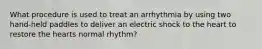 What procedure is used to treat an arrhythmia by using two hand-held paddles to deliver an electric shock to the heart to restore the hearts normal rhythm?