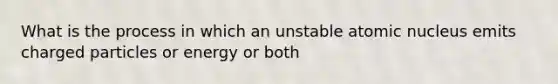 What is the process in which an unstable atomic nucleus emits charged particles or energy or both