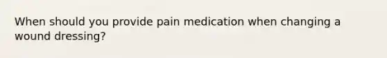 When should you provide pain medication when changing a wound dressing?