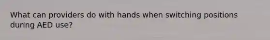 What can providers do with hands when switching positions during AED use?