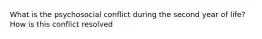 What is the psychosocial conflict during the second year of life? How is this conflict resolved