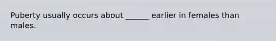 Puberty usually occurs about ______ earlier in females than males.