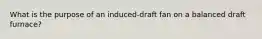 What is the purpose of an induced-draft fan on a balanced draft furnace?