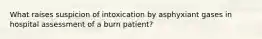 What raises suspicion of intoxication by asphyxiant gases in hospital assessment of a burn patient?