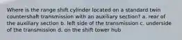 Where is the range shift cylinder located on a standard twin countershaft transmission with an auxiliary section? a. rear of the auxiliary section b. left side of the transmission c. underside of the transmission d. on the shift tower hub