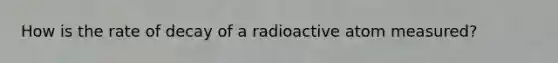 How is the rate of decay of a radioactive atom measured?