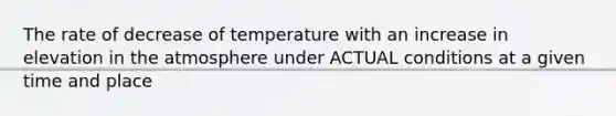 The rate of decrease of temperature with an increase in elevation in the atmosphere under ACTUAL conditions at a given time and place