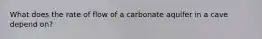 What does the rate of flow of a carbonate aquifer in a cave depend on?