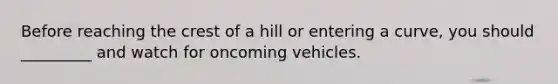 Before reaching the crest of a hill or entering a curve, you should _________ and watch for oncoming vehicles.