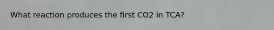 What reaction produces the first CO2 in TCA?