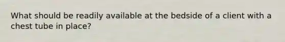 What should be readily available at the bedside of a client with a chest tube in place?