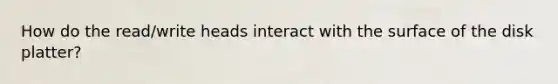 How do the read/write heads interact with the surface of the disk platter?