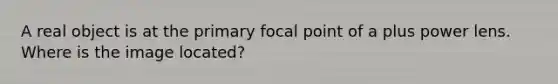 A real object is at the primary focal point of a plus power lens. Where is the image located?