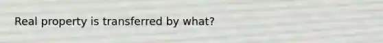 Real property is transferred by what?