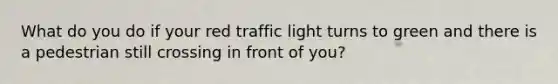 What do you do if your red traffic light turns to green and there is a pedestrian still crossing in front of you?