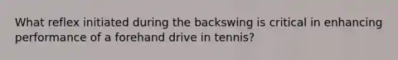 What reflex initiated during the backswing is critical in enhancing performance of a forehand drive in tennis?