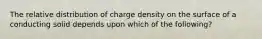 The relative distribution of charge density on the surface of a conducting solid depends upon which of the following?