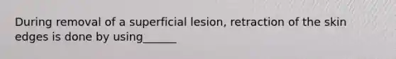 During removal of a superficial lesion, retraction of the skin edges is done by using______