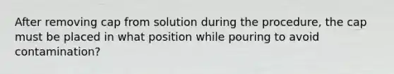 After removing cap from solution during the procedure, the cap must be placed in what position while pouring to avoid contamination?