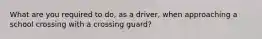 What are you required to do, as a driver, when approaching a school crossing with a crossing guard?