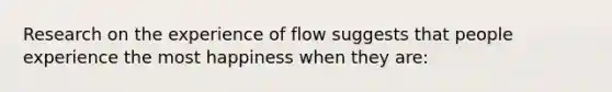 Research on the experience of flow suggests that people experience the most happiness when they are: