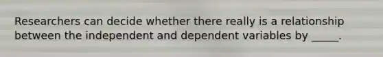 Researchers can decide whether there really is a relationship between the independent and dependent variables by _____.