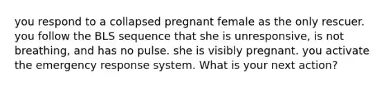 you respond to a collapsed pregnant female as the only rescuer. you follow the BLS sequence that she is unresponsive, is not breathing, and has no pulse. she is visibly pregnant. you activate the emergency response system. What is your next action?