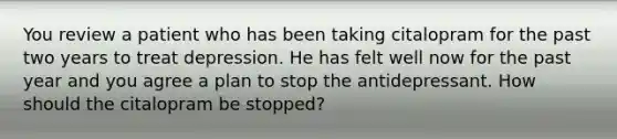 You review a patient who has been taking citalopram for the past two years to treat depression. He has felt well now for the past year and you agree a plan to stop the antidepressant. How should the citalopram be stopped?