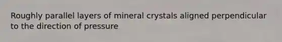 Roughly parallel layers of mineral crystals aligned perpendicular to the direction of pressure