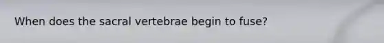 When does the sacral vertebrae begin to fuse?