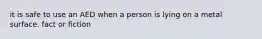 it is safe to use an AED when a person is lying on a metal surface. fact or fiction