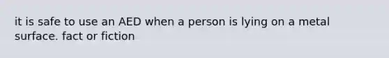 it is safe to use an AED when a person is lying on a metal surface. fact or fiction