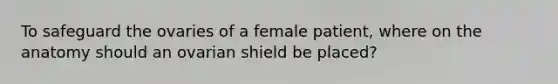 To safeguard the ovaries of a female patient, where on the anatomy should an ovarian shield be placed?