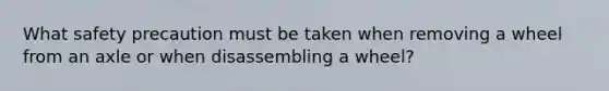 What safety precaution must be taken when removing a wheel from an axle or when disassembling a wheel?
