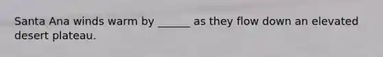 Santa Ana winds warm by ______ as they flow down an elevated desert plateau.