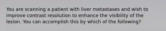 You are scanning a patient with liver metastases and wish to improve contrast resolution to enhance the visibility of the lesion. You can accomplish this by which of the following?