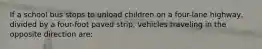 If a school bus stops to unload children on a four-lane highway, divided by a four-foot paved strip, vehicles traveling in the opposite direction are: