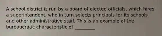 A school district is run by a board of elected officials, which hires a superintendent, who in turn selects principals for its schools and other administrative staff. This is an example of the bureaucratic characteristic of _________