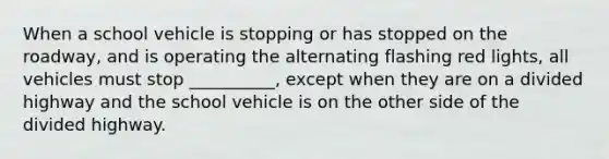 When a school vehicle is stopping or has stopped on the roadway, and is operating the alternating flashing red lights, all vehicles must stop __________, except when they are on a divided highway and the school vehicle is on the other side of the divided highway.