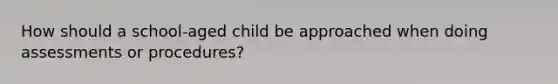 How should a school-aged child be approached when doing assessments or procedures?