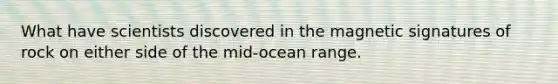 What have scientists discovered in the magnetic signatures of rock on either side of the mid-ocean range.