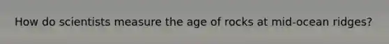 How do scientists measure the age of rocks at mid-ocean ridges?