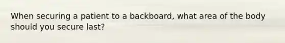 When securing a patient to a backboard, what area of the body should you secure last?