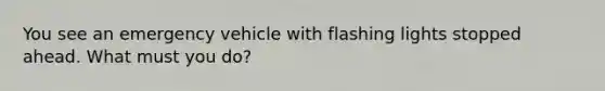 You see an emergency vehicle with flashing lights stopped ahead. What must you do?