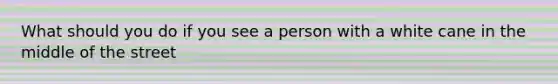 What should you do if you see a person with a white cane in the middle of the street