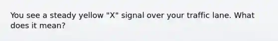 You see a steady yellow "X" signal over your traffic lane. What does it mean?