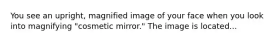 You see an upright, magnified image of your face when you look into magnifying "cosmetic mirror." The image is located...