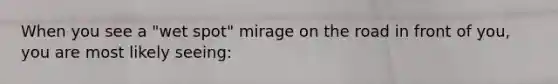 When you see a "wet spot" mirage on the road in front of you, you are most likely seeing: